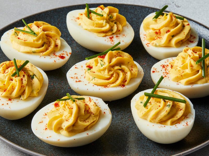 A platter of deviled eggs with chives and paprika
